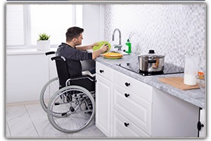 Man in wheelchair washing dishes in modified kitchen